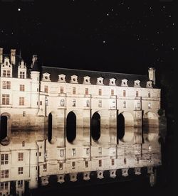 Digital composite image of historic building against sky at night