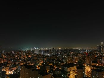 Illuminated cityscape against clear sky at night