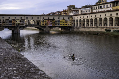 Ponte vecchio over arno river with its colorful little houses hanging - florence, tuscany, italy