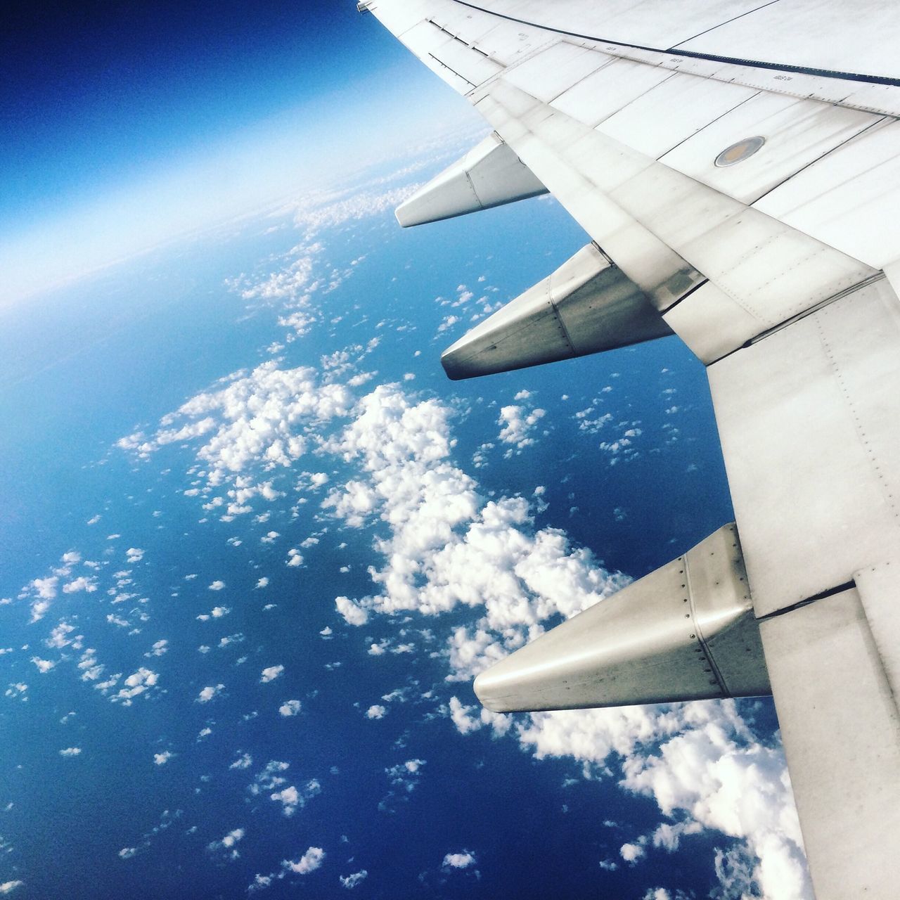 aircraft wing, airplane, transportation, air vehicle, mode of transport, flying, part of, aerial view, cropped, journey, travel, sky, mid-air, sea, on the move, scenics, airplane wing, blue, nature, beauty in nature