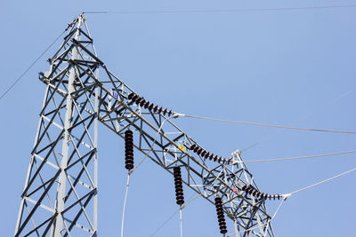 Low angle view of electricity pylon against clear sky