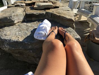 Low section of woman sitting on rock