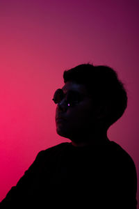 Portrait of young man looking away over pink background