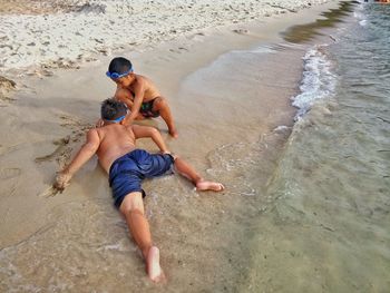 High angle view of shirtless brothers playing at beach