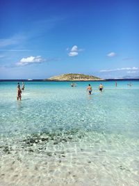 People on beach against blue sky