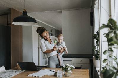 Multitasking mother taking care of baby and working from home