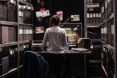 Rear view of man working in library