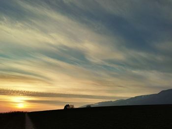 Silhouette people on land against sky during sunset