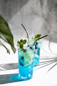 Curacao blue cocktail with fresh blueberries and lemon wedges, garnished with mint with shadows