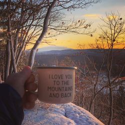 Close-up of text on hand against sky at sunset