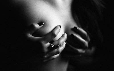 Close-up of sensuous woman covering breasts with hands