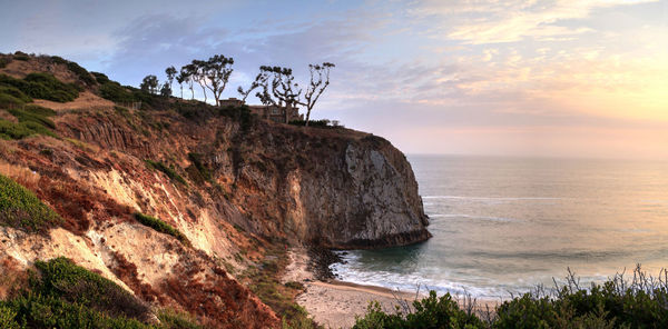 Scenic view of cliff by sea against sky