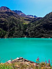 Scenic view of swimming pool by mountains against blue sky