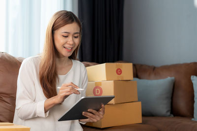 Portrait of young woman using digital tablet while sitting on sofa at home