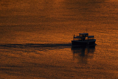 Boat sailing in sea against sky during sunset