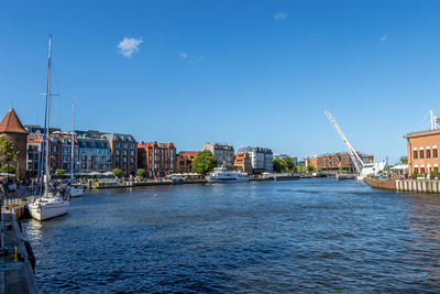 Scenic view of river by buildings against blue sky