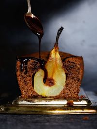 Close-up of chocolate dripping from spoon onto cake