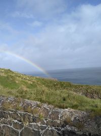 Scenic view of rainbow over sea against sky