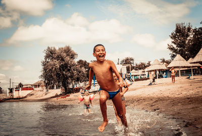 Full length of shirtless young man on beach