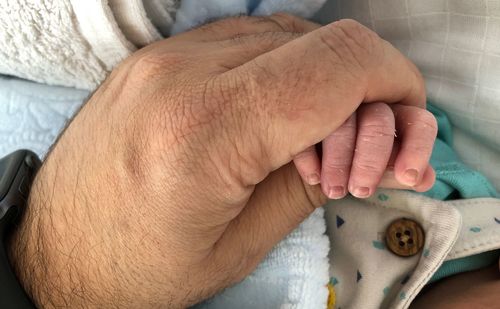 Close-up of man holding baby hand