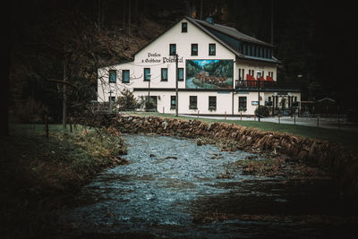 River amidst houses and trees against sky