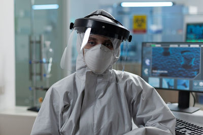 Portrait of scientist wearing face shield sitting at laboratory