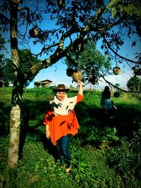 Portrait of man standing by tree on field