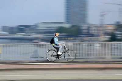 Blurred motion of woman riding bicycle on road in city