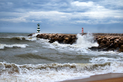 Lighthouse on beach against sky