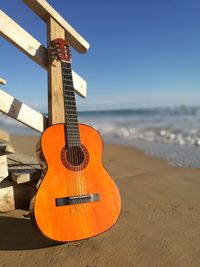 Guitar on beach against sky