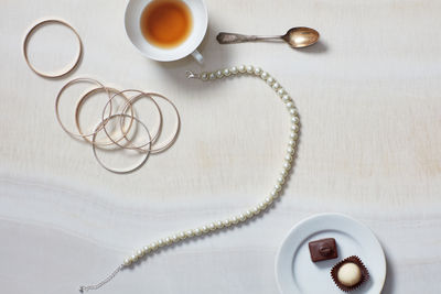 Still life with necklace, bracelet, tea, chocolates