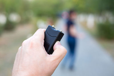 Hand with electric shocker, the criminal catches up with woman for robbery.