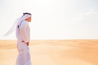 Woman standing on sand at beach against sky