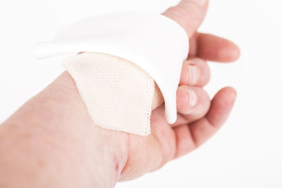 Close-up of hand holding ring over white background