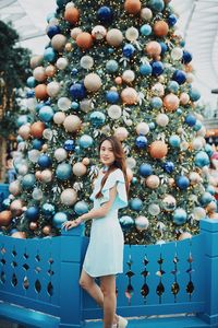 Portrait of smiling young woman standing by christmas tree outdoors