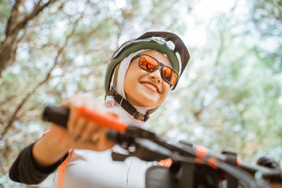 Low angle view of smiling woman wearing sunglasses