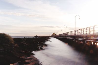 Bridge over sea against sky during sunset