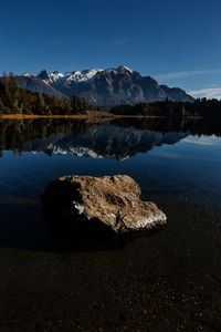 Rocks by lake against blue sky