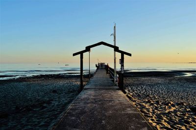 Pier over sea against clear sky during sunset