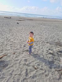 Full length of boy on shore at beach against sky