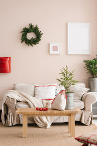 Stylish christmas living room interior with sofa, coffee table, christmas tree and wreath, mailbox