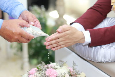Midsection of woman holding flowers on table