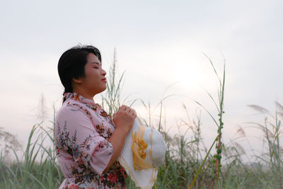 Side view of woman with closed eye standing on field