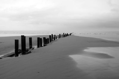 Wooden posts on beach against sky