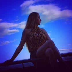 Woman looking away while sitting against sky