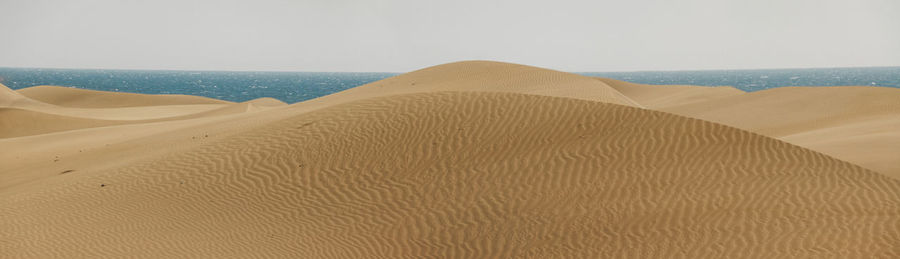 Scenic view of sand dunes against clear sky