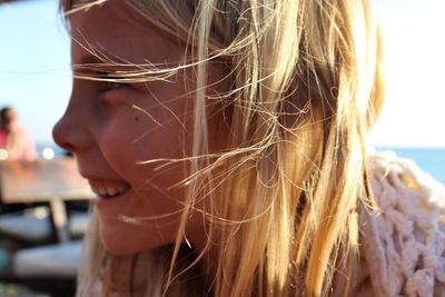 Close-up of girl with tousled hair smiling outdoors