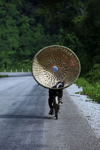 Low section of person riding bicycle with wicker container on road