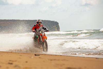 Man riding horse on beach against sky