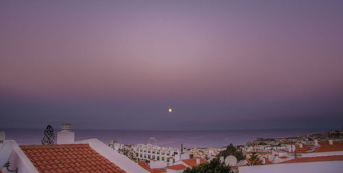 High angle view of houses by sea against sky during sunset